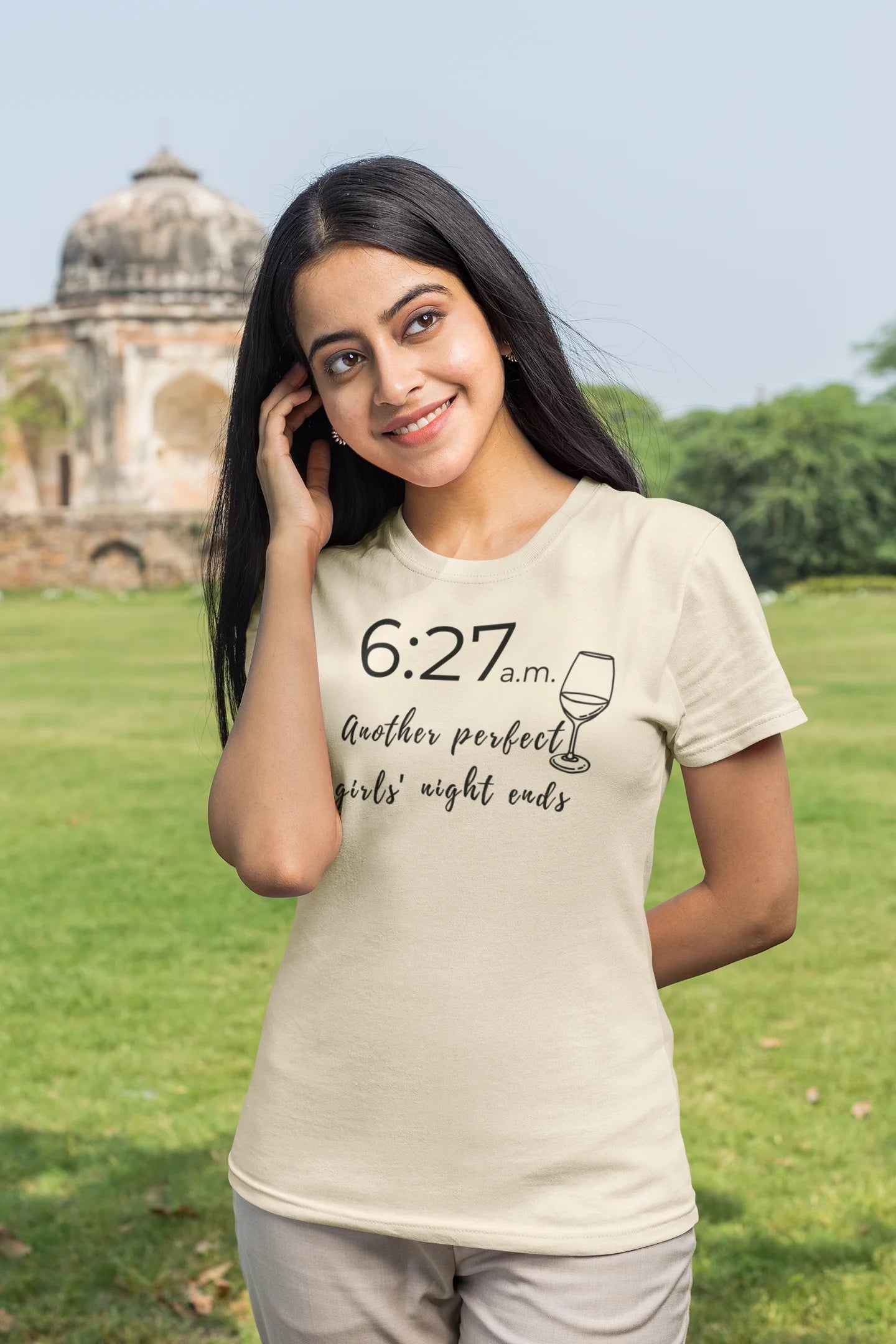 Woman wearing a beige t-shirt with text in a park