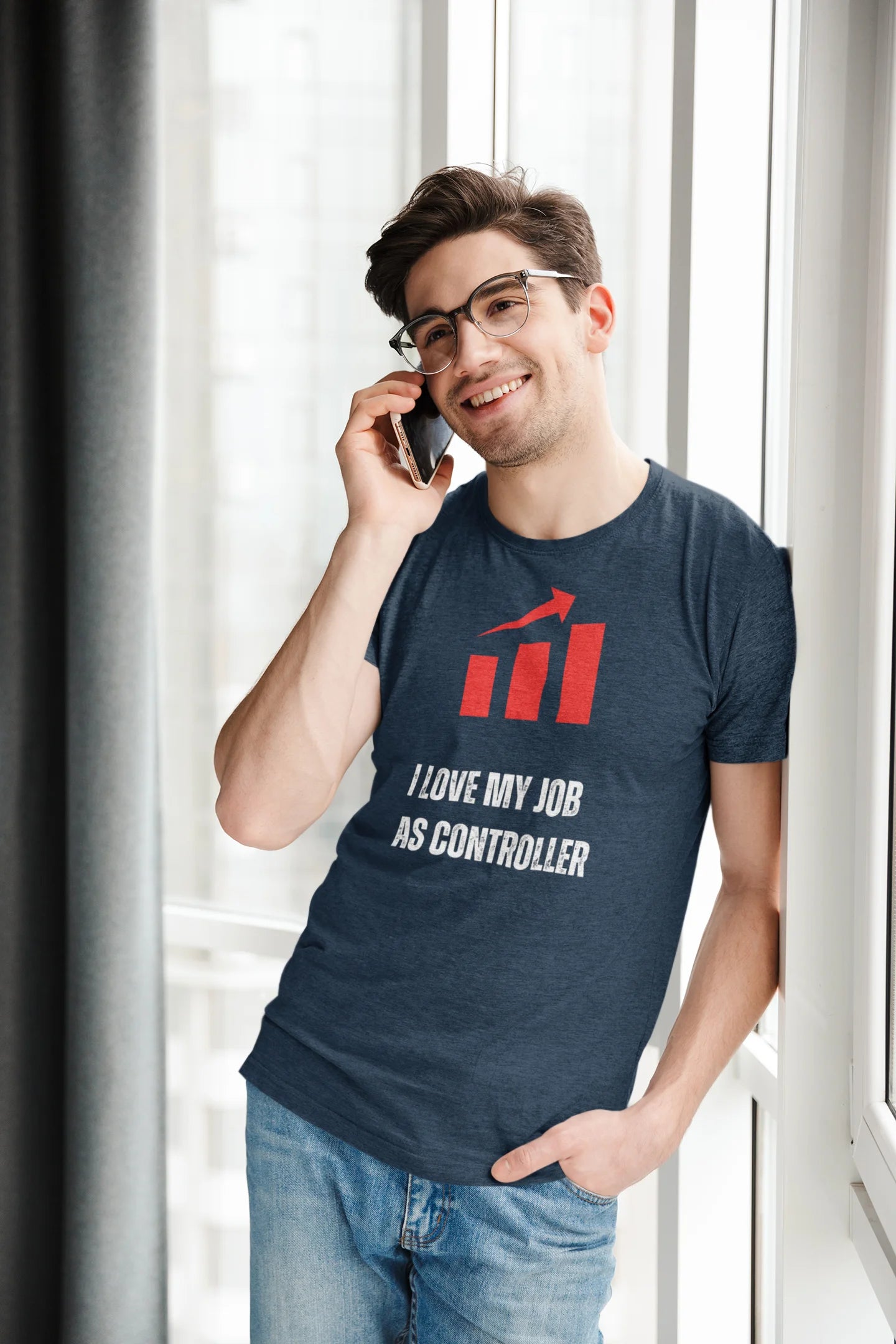 Finance Controller Shirt Man wearing a t-shirt with a graphic and text, standing by a window.