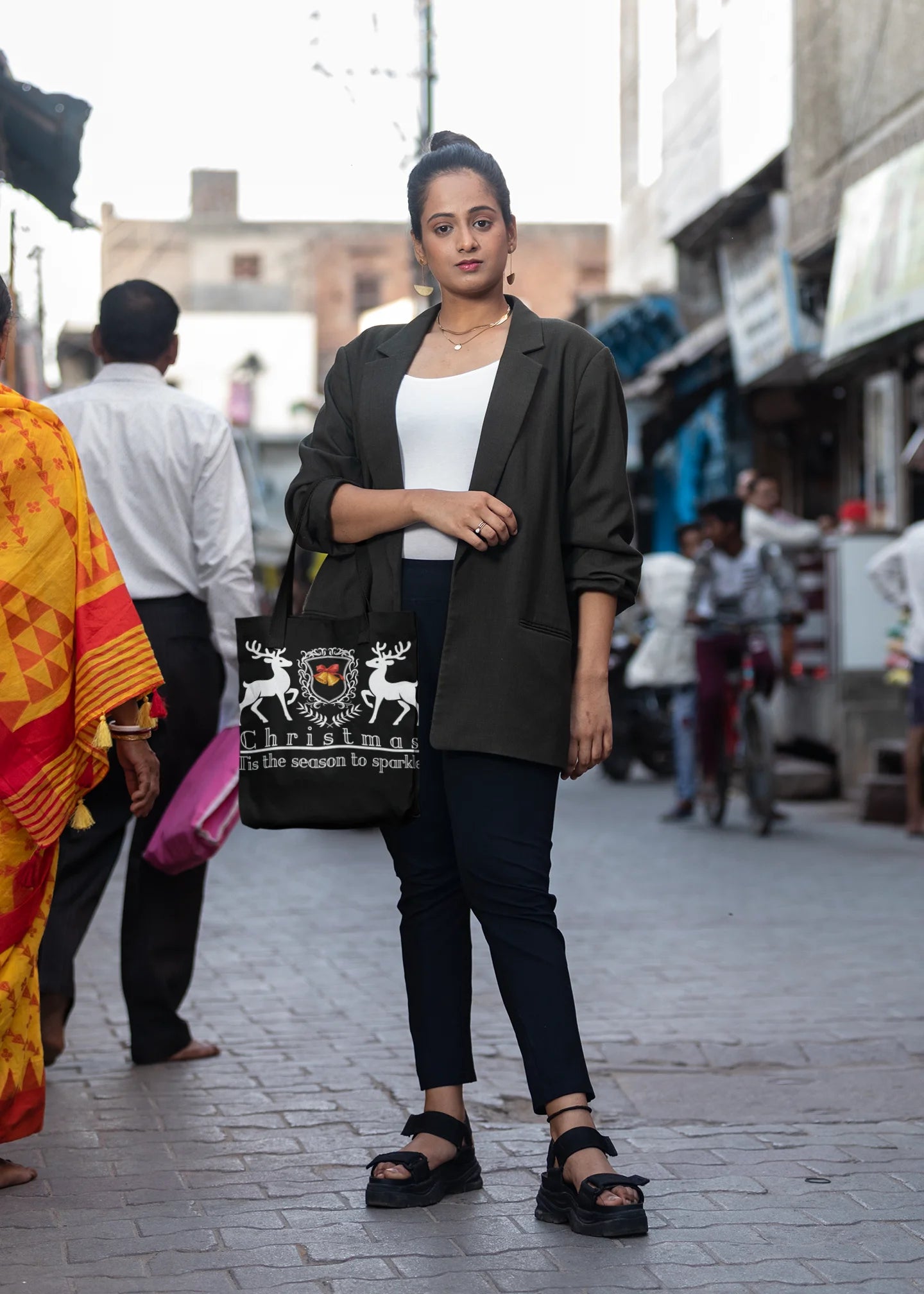 Woman walking on a street holding a black bag with white designs