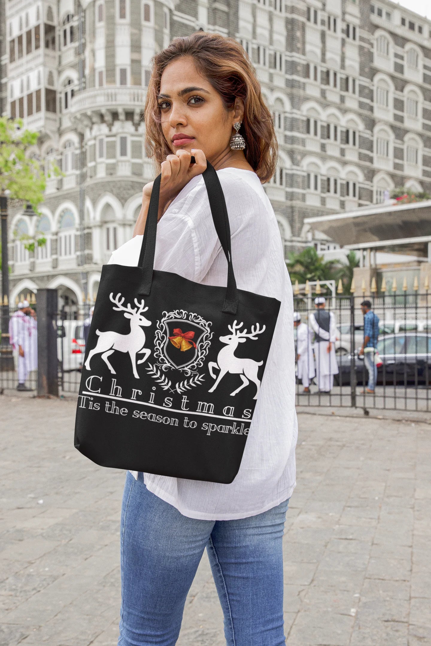 Woman holding a black tote bag with Christmas design in an urban setting