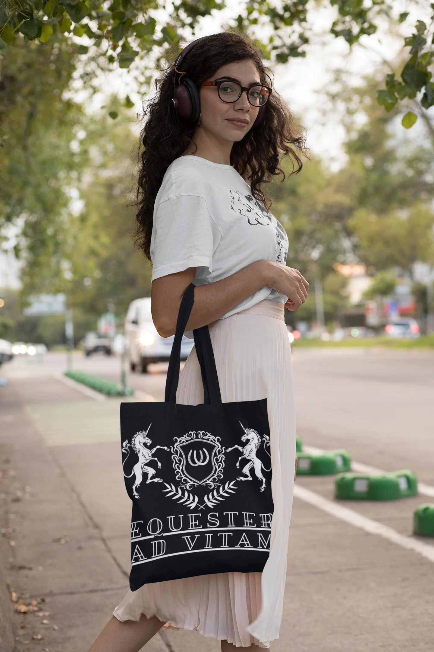 Woman holding a black tote bag with white design and text on a street.