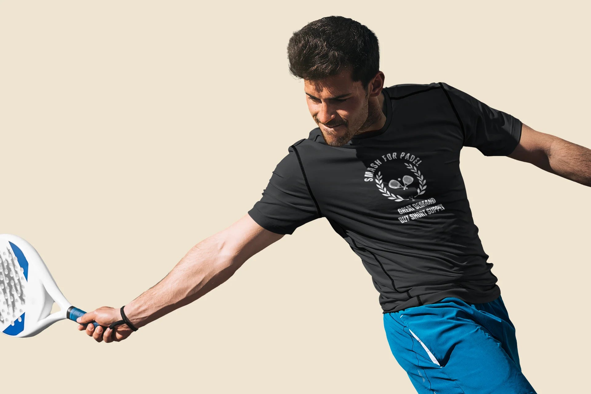 Man playing paddle tennis wearing a black t-shirt with text and blue shorts on a beige background