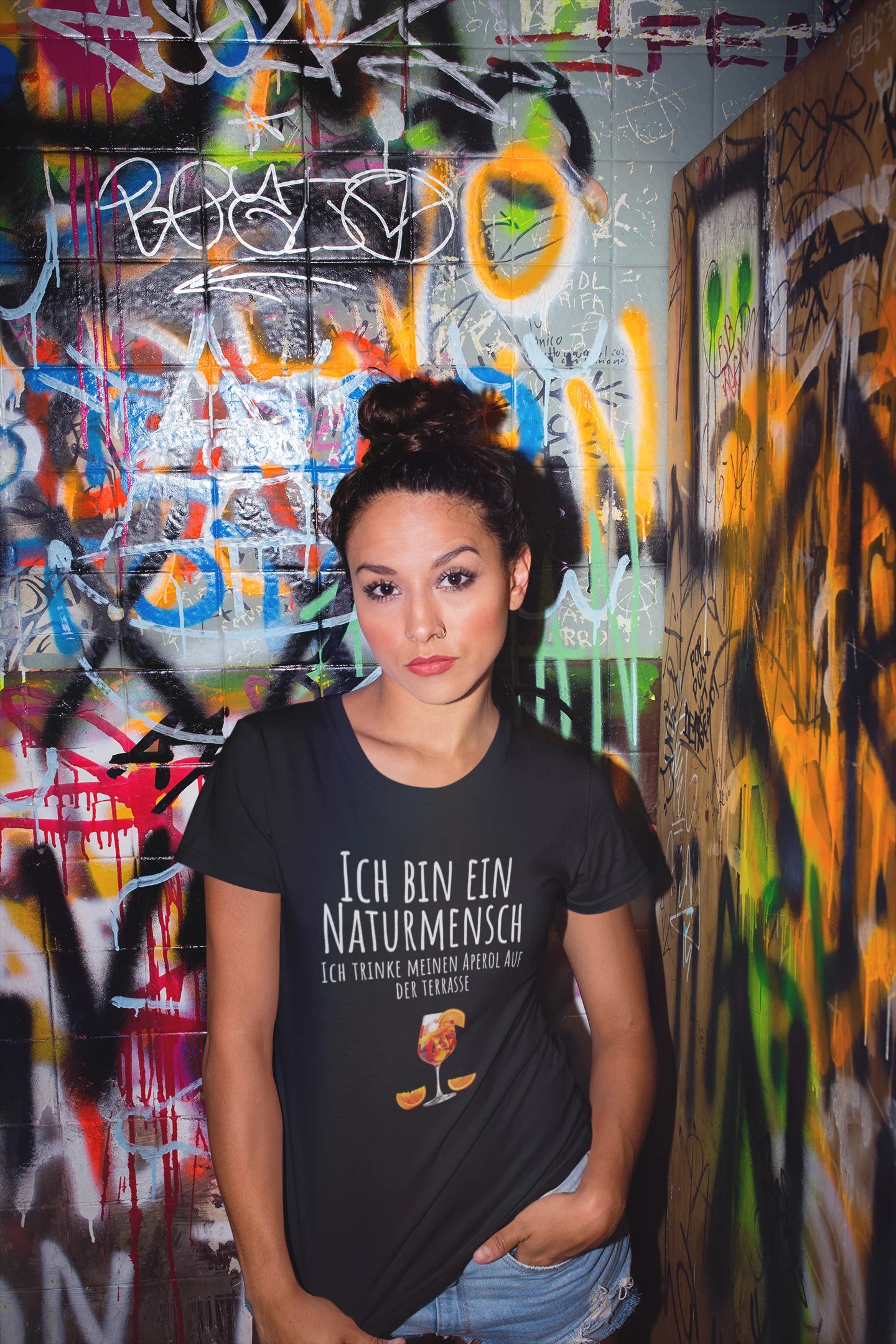 Woman wearing a black t-shirt with text in front of a colorful graffiti wall
