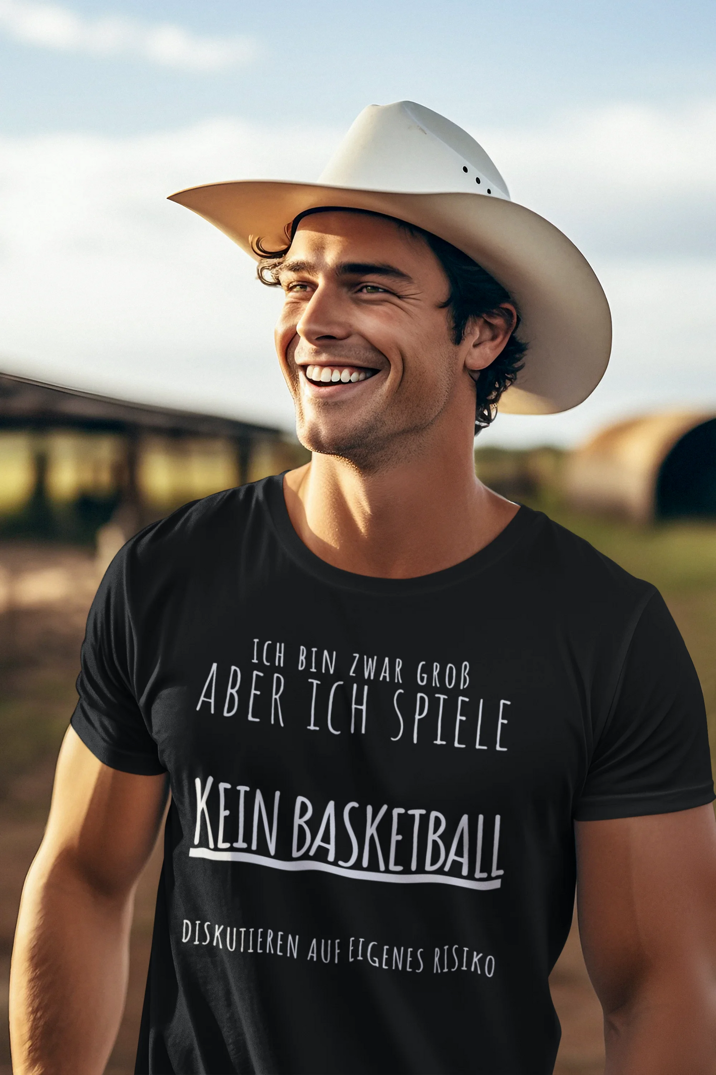 Man wearing a black t-shirt with German text, smiling outdoors.