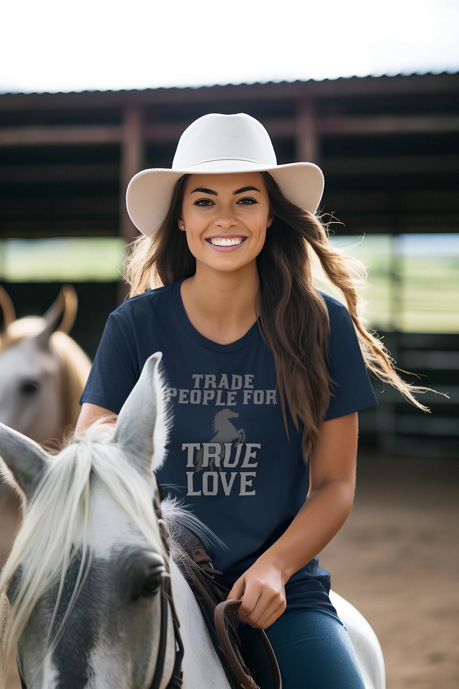 Woman riding a horse wearing a blue t-shirt with text, standing in a stable.