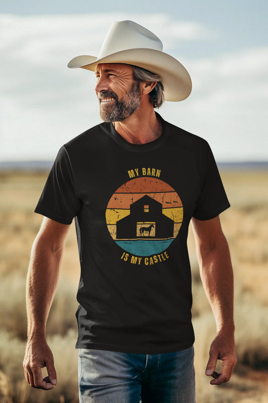 Equestrian Funny Tee Man wearing a black t-shirt with a graphic design of a barn and text, standing in a desert landscape.