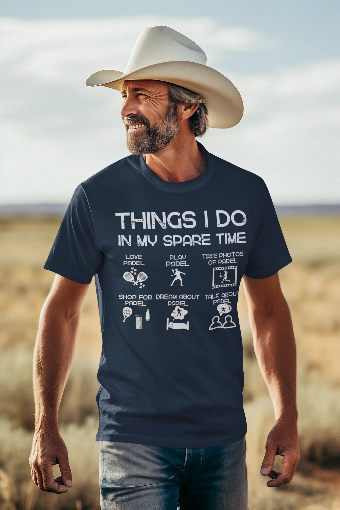 Man wearing a navy blue t-shirt with text and graphics, standing in a desert landscape.