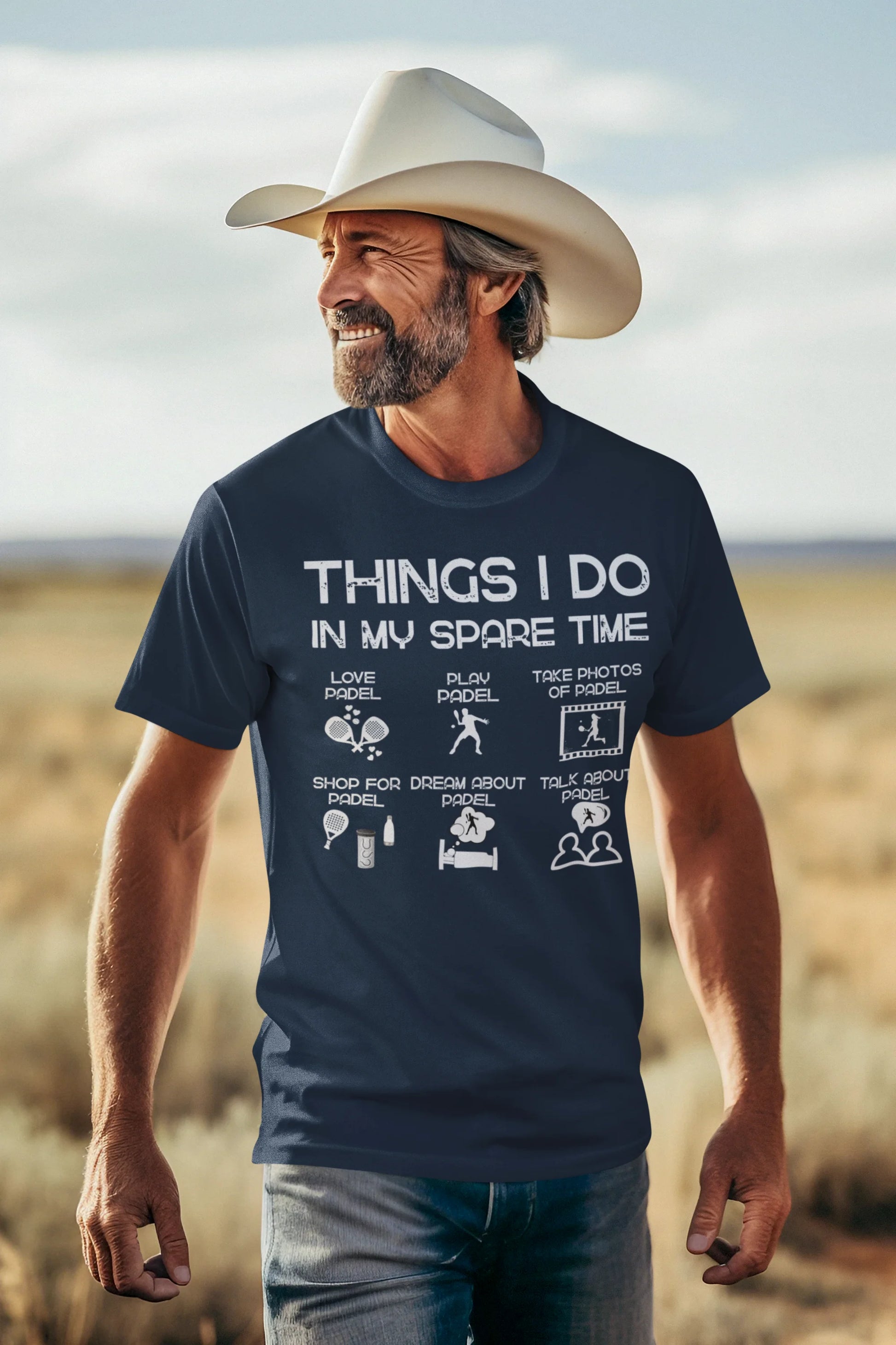 Man wearing a navy blue t-shirt with text and graphics, standing in a desert landscape.