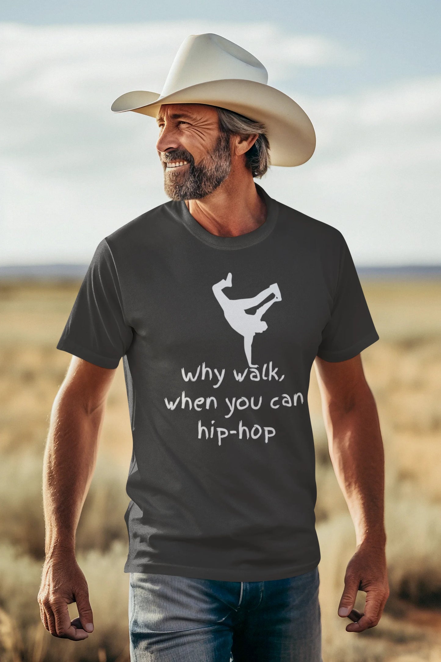 Man wearing a gray t-shirt with a graphic and text, standing in a desert landscape.