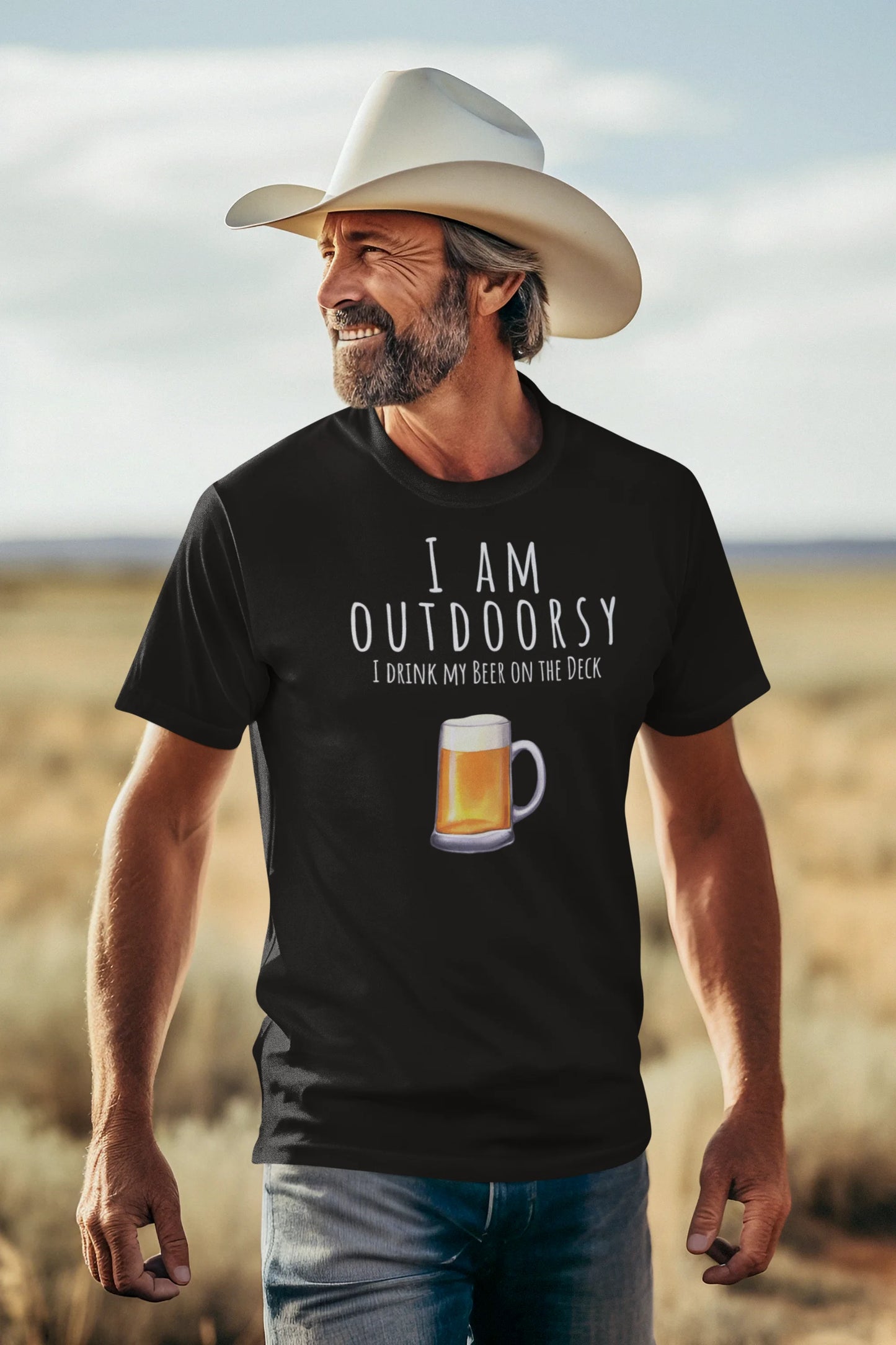 Man wearing a black t-shirt with 'I AM OUTDOORSY I DRANK MY BEER ON THE DECK' text and a beer graphic, standing in a desert landscape.