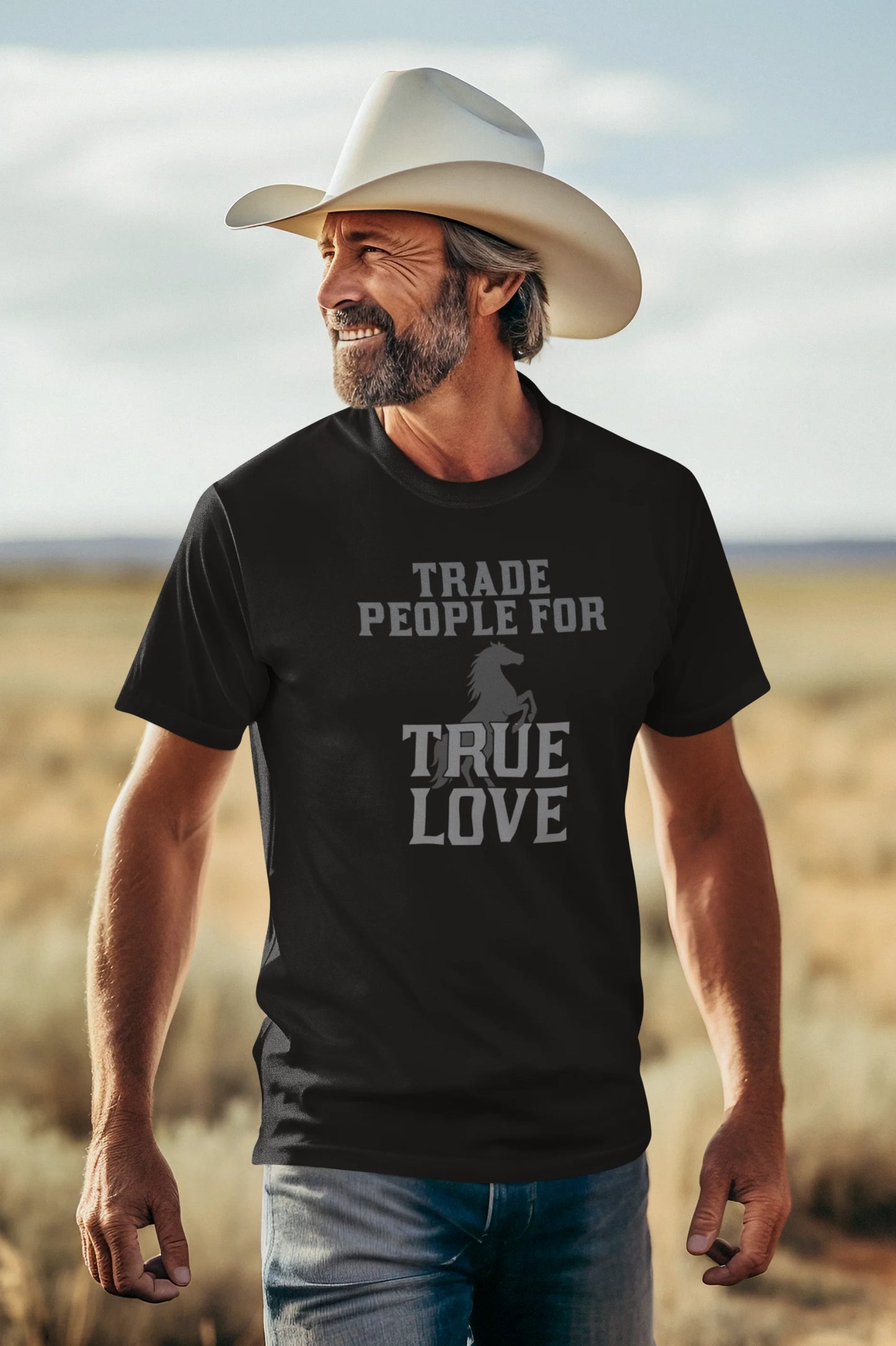 Man wearing a black t-shirt with a graphic and text, standing in a desert landscape.
