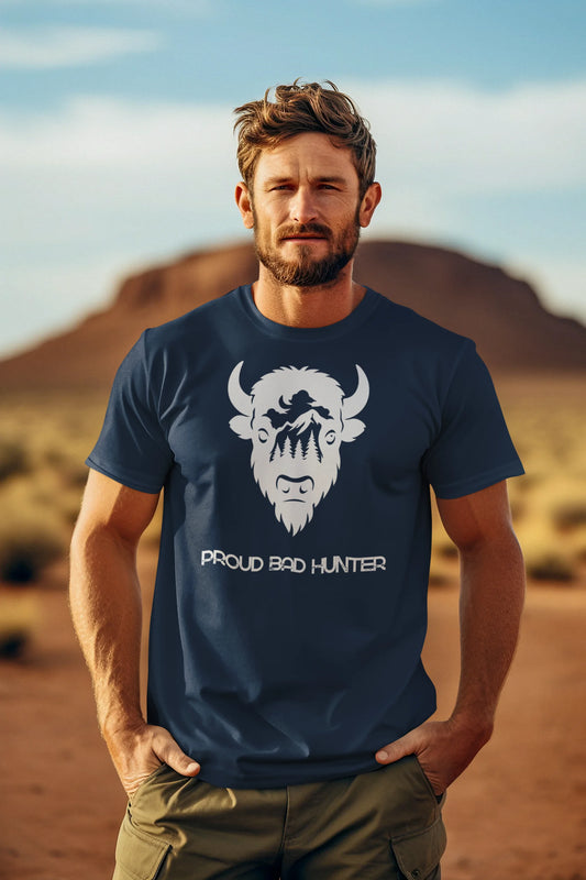Man wearing a navy blue t-shirt with a graphic design and text, standing in a desert landscape.