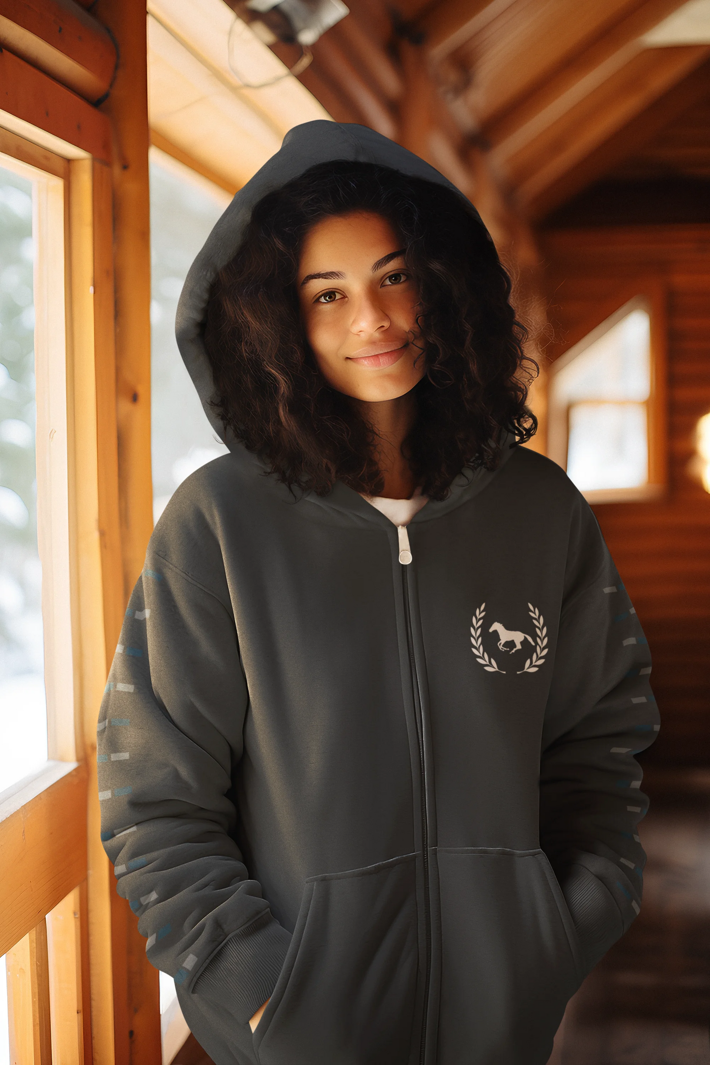 Person wearing a dark gray hoodie with a logo inside a wooden cabin.